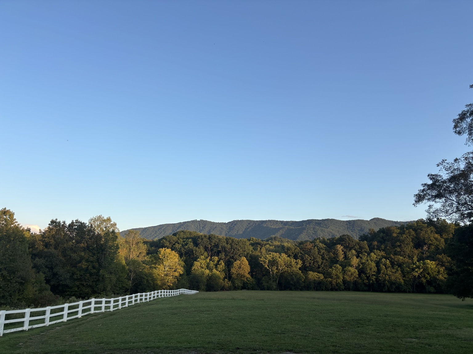 The open ceremony field at Sterling Hills framed by white fencing and the Smoky Mountains